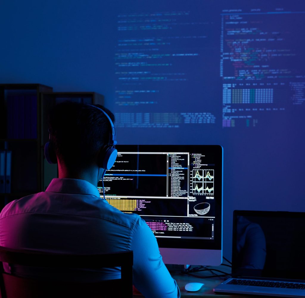 Developer working on code late at night, view from the back